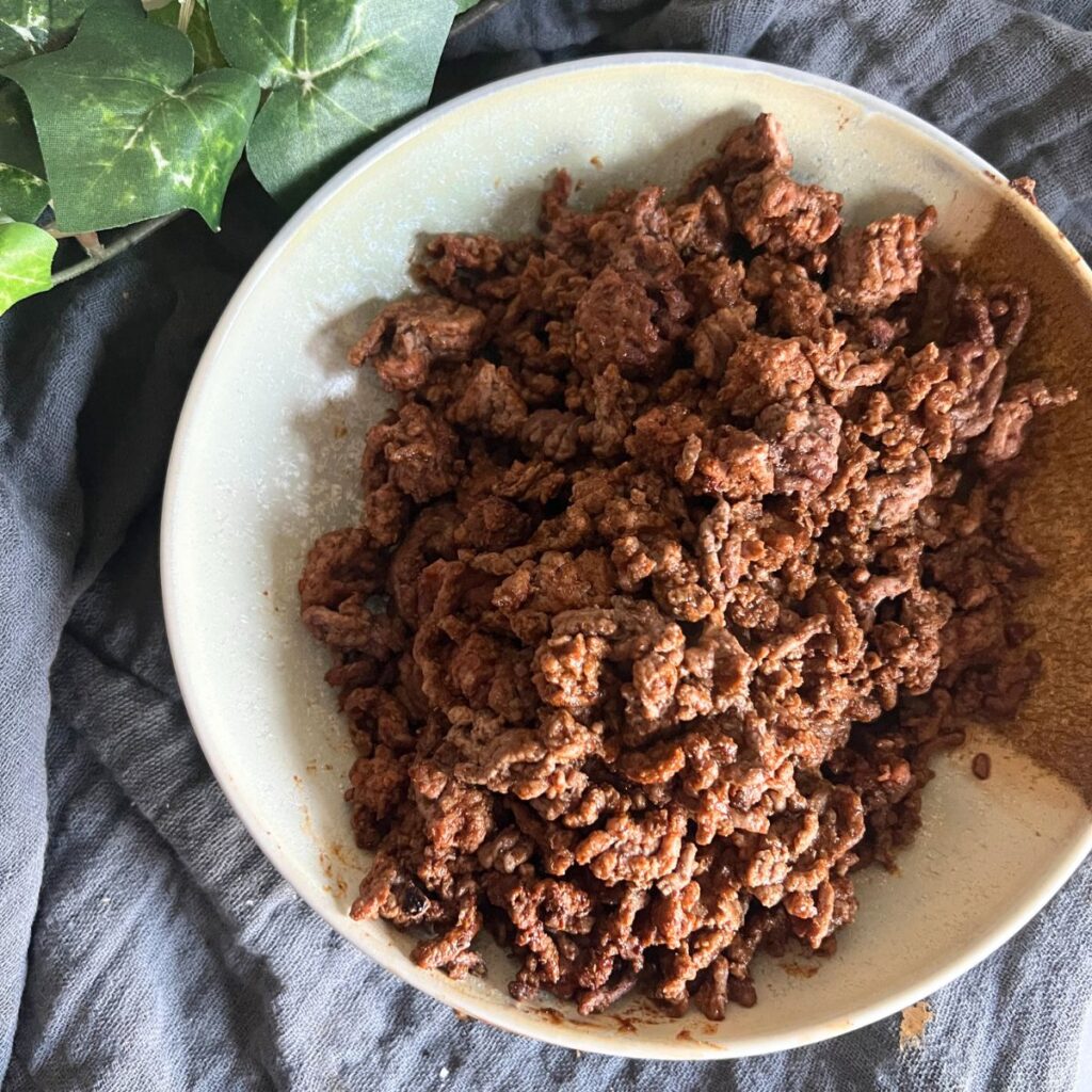 Cooked ground beef seasoned with taco seasonings on a Blackstone griddle. 