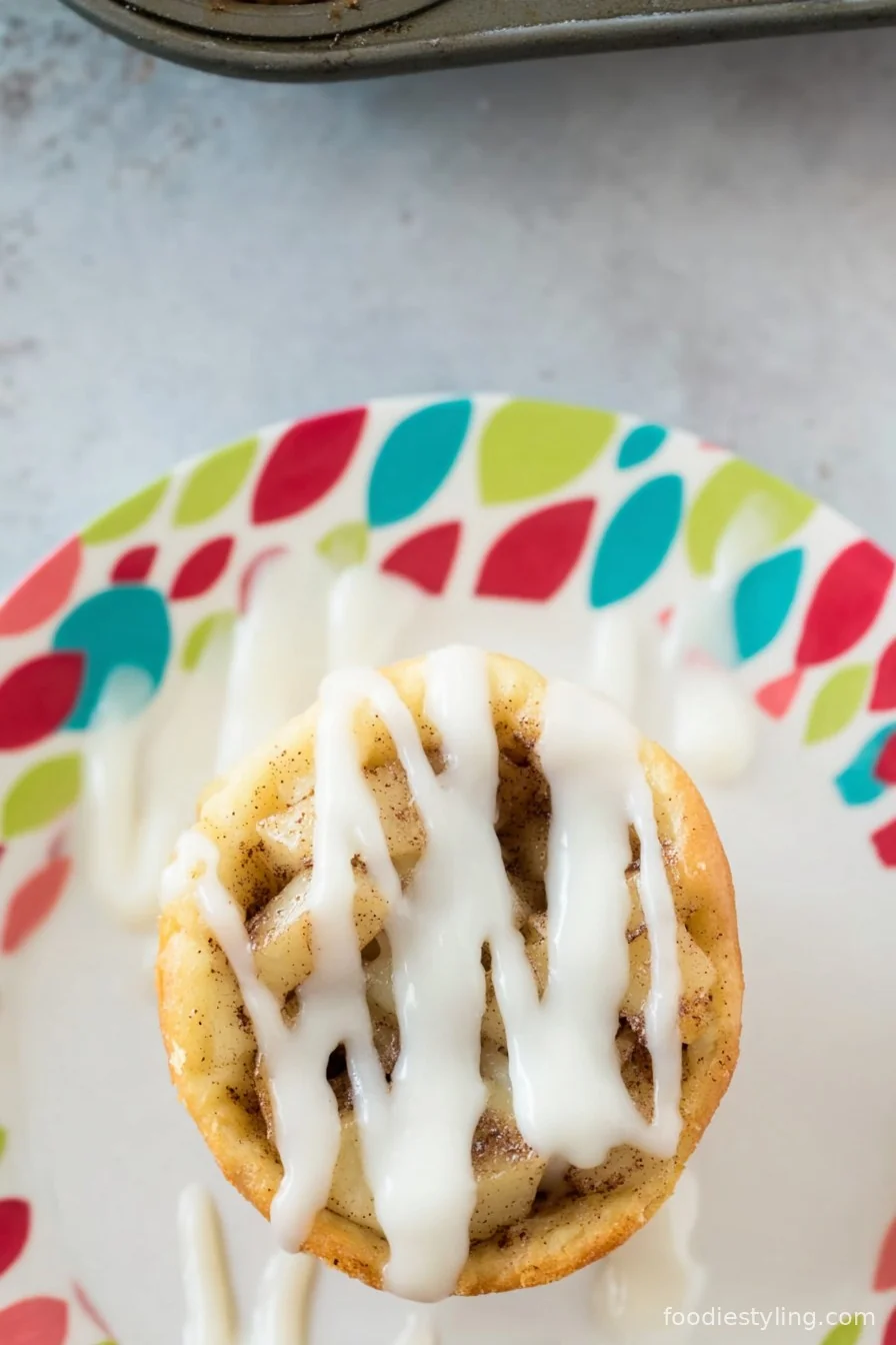 Cinnamon Roll Apple Pie Cups baked golden brown on a platter, drizzled with sweet icing